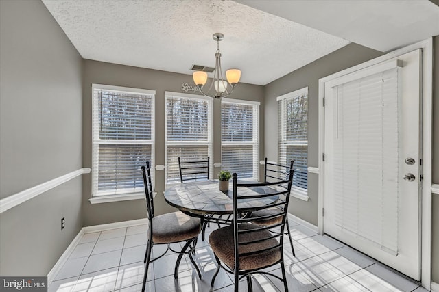 tiled dining area with an inviting chandelier, a textured ceiling, and a wealth of natural light