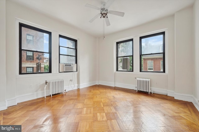 empty room with radiator heating unit, light parquet floors, cooling unit, and ceiling fan