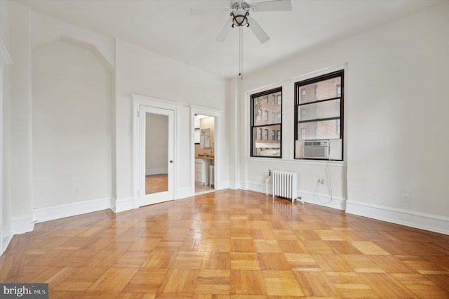 empty room featuring radiator heating unit, light parquet flooring, cooling unit, and ceiling fan