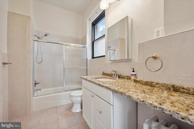 full bathroom with tile patterned flooring, combined bath / shower with glass door, decorative backsplash, vanity, and tile walls