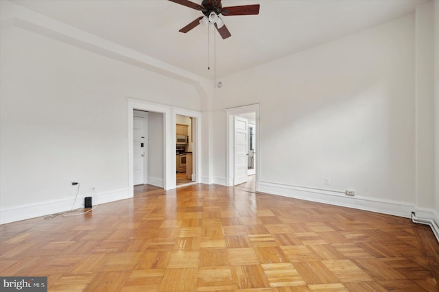 unfurnished room featuring ceiling fan, a towering ceiling, and light parquet flooring