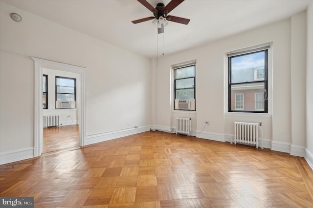 empty room with radiator, a wealth of natural light, and light parquet floors