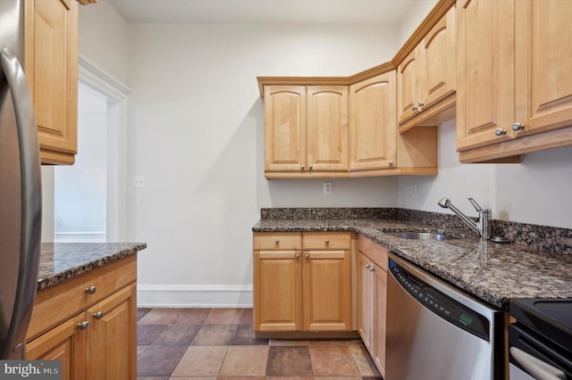 kitchen featuring light brown cabinets, sink, appliances with stainless steel finishes, and dark stone counters