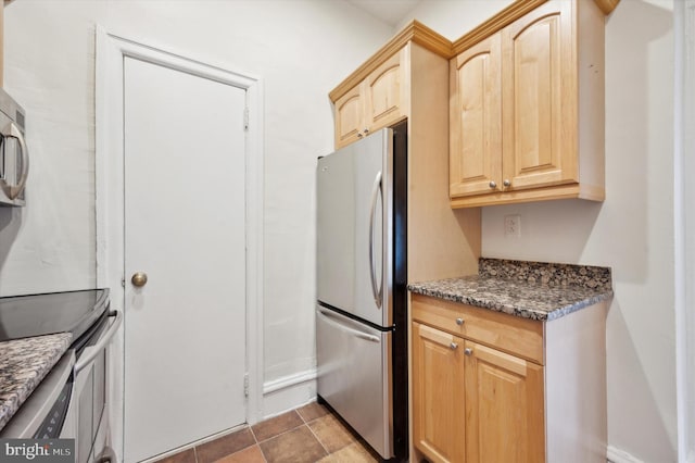 kitchen with appliances with stainless steel finishes, light brown cabinets, and dark stone countertops