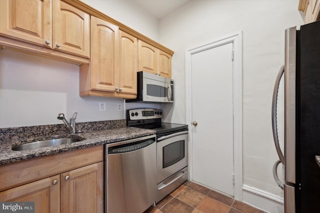 kitchen with dark stone countertops, light brown cabinetry, sink, and appliances with stainless steel finishes