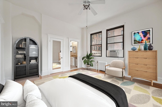 bedroom featuring ensuite bath, ceiling fan, cooling unit, radiator heating unit, and light hardwood / wood-style floors