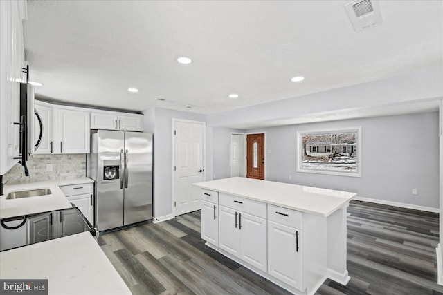 kitchen featuring white cabinets, a center island, stainless steel refrigerator with ice dispenser, and sink