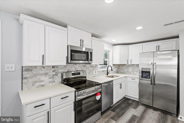 kitchen featuring appliances with stainless steel finishes, a textured ceiling, white cabinetry, sink, and dark hardwood / wood-style flooring