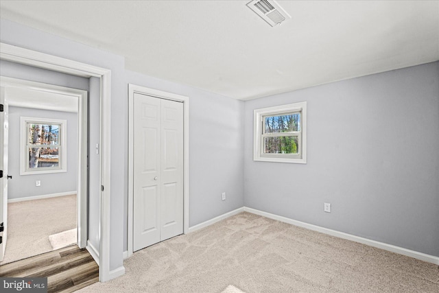 unfurnished bedroom featuring a closet and light colored carpet