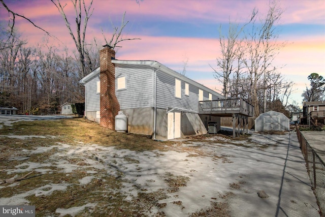 property exterior at dusk with a wooden deck and a storage shed