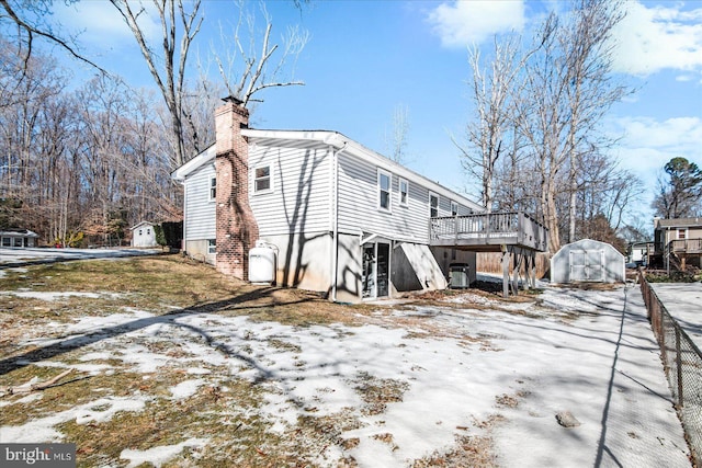 view of snowy exterior with a storage unit and a deck