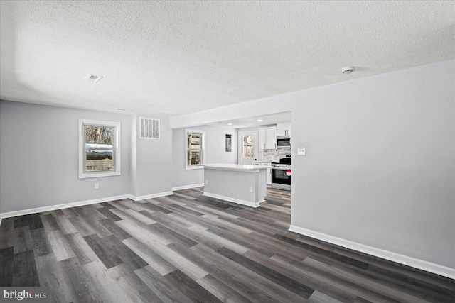 unfurnished living room featuring a textured ceiling and dark hardwood / wood-style floors