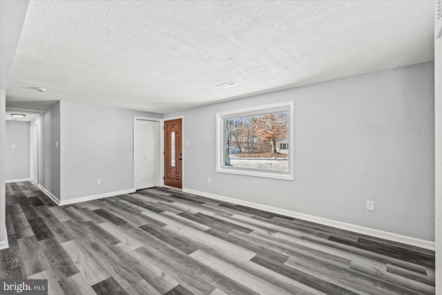 empty room featuring a textured ceiling and dark hardwood / wood-style floors