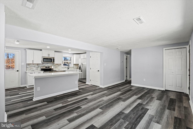 kitchen with white cabinets, appliances with stainless steel finishes, dark wood-type flooring, sink, and backsplash