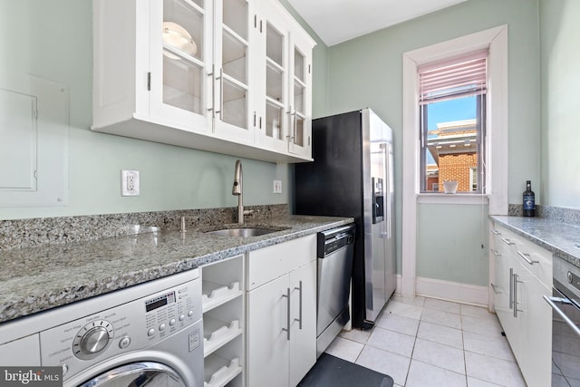 kitchen featuring light tile patterned floors, washer / dryer, a sink, white cabinets, and appliances with stainless steel finishes