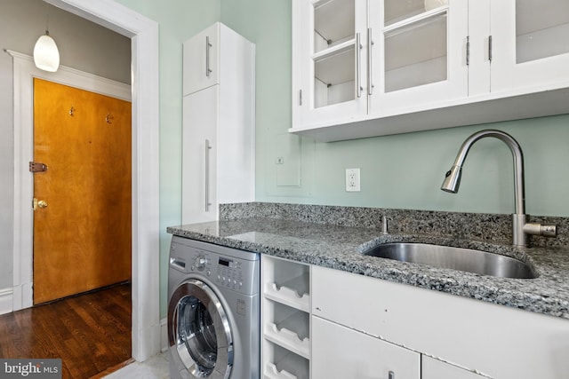 laundry area featuring wood finished floors, washer / clothes dryer, cabinet space, and a sink