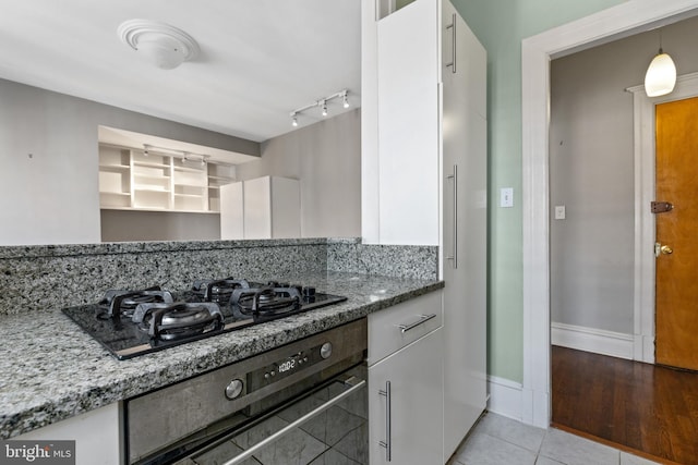 kitchen featuring light stone counters, light tile patterned flooring, white cabinets, black gas cooktop, and wall oven