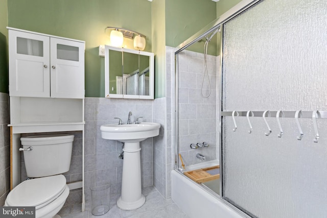 full bathroom with tile patterned floors, enclosed tub / shower combo, toilet, and tile walls