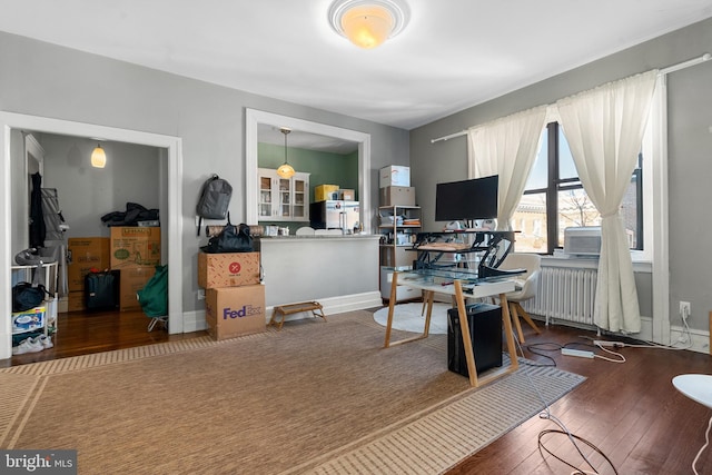 office area featuring radiator heating unit, baseboards, and hardwood / wood-style flooring