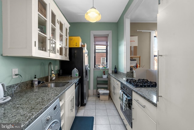 kitchen featuring light tile patterned floors, washer / dryer, a sink, black appliances, and white cabinetry