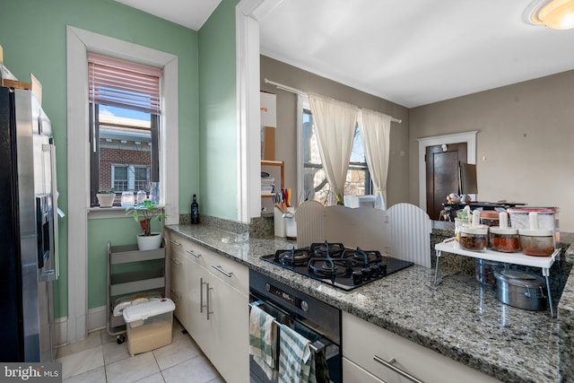 kitchen with wall oven, black gas stovetop, a healthy amount of sunlight, and stainless steel fridge