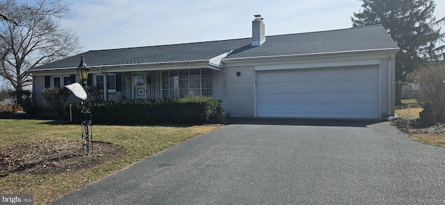 ranch-style house featuring a front lawn, a garage, driveway, and a chimney