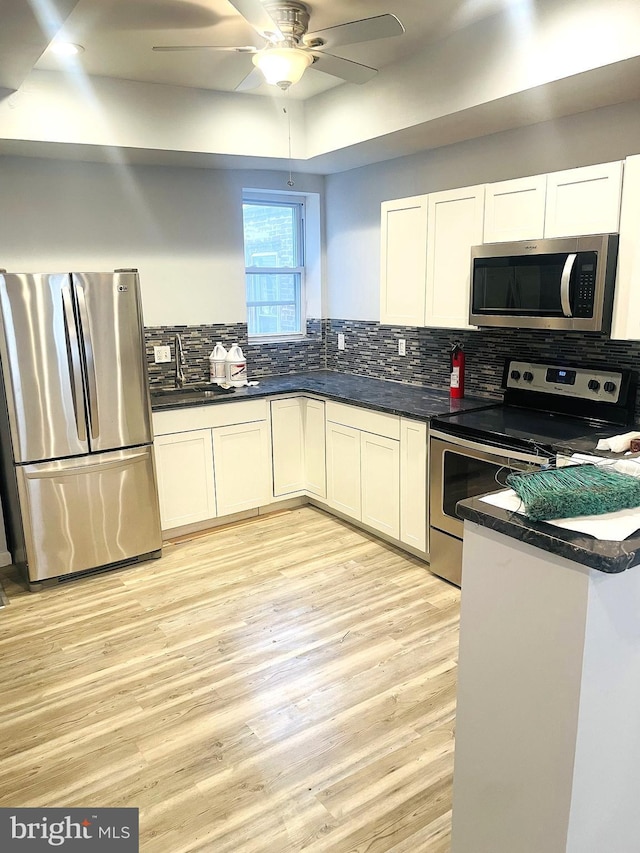 kitchen featuring light wood-type flooring, stainless steel appliances, ceiling fan, sink, and white cabinets