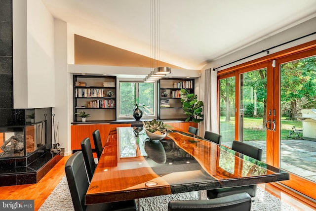 dining area featuring a tile fireplace, french doors, lofted ceiling, and hardwood / wood-style flooring