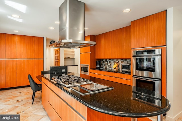 kitchen with dark stone counters, island range hood, stainless steel appliances, light tile patterned floors, and a center island