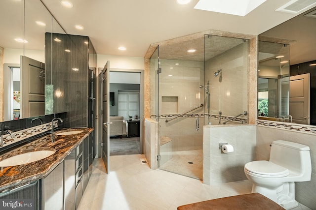 bathroom featuring vanity, a shower with door, a skylight, toilet, and tasteful backsplash