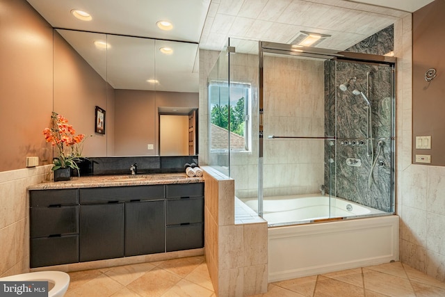 bathroom featuring tile patterned flooring, vanity, combined bath / shower with glass door, and tile walls