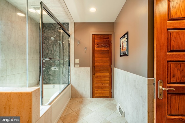 bathroom with tile patterned flooring, shower / bath combination with glass door, and tile walls