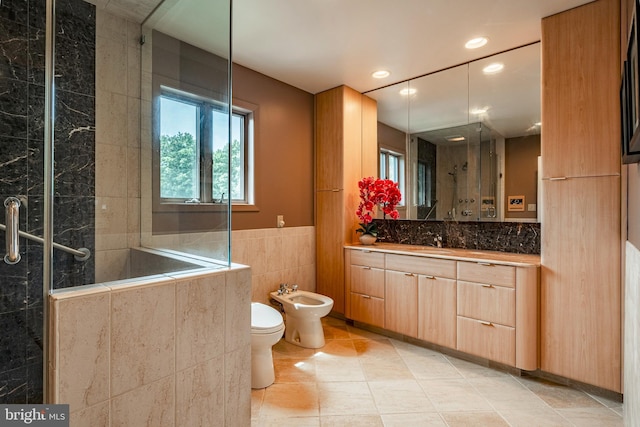 bathroom featuring tile patterned floors, vanity, a bidet, tile walls, and toilet