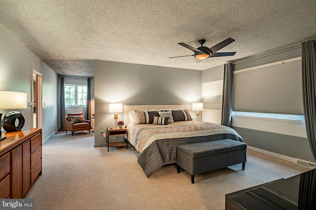 carpeted bedroom featuring ceiling fan and a textured ceiling