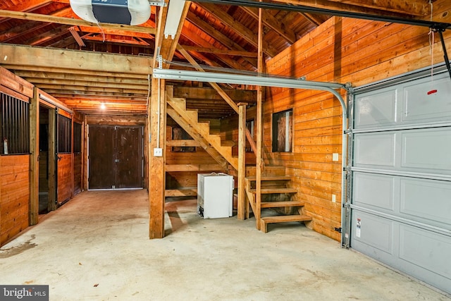 garage with a garage door opener and wood walls