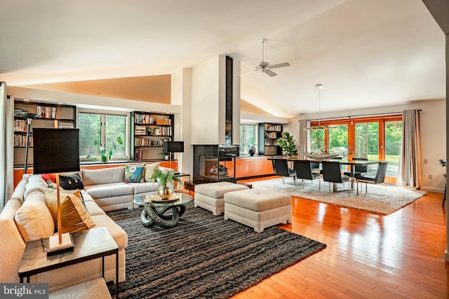 living room featuring ceiling fan, light hardwood / wood-style floors, and vaulted ceiling