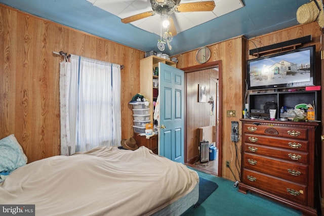 carpeted bedroom featuring ceiling fan and wood walls