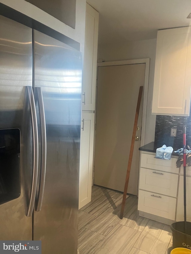 kitchen featuring white cabinets, stainless steel fridge with ice dispenser, and tasteful backsplash