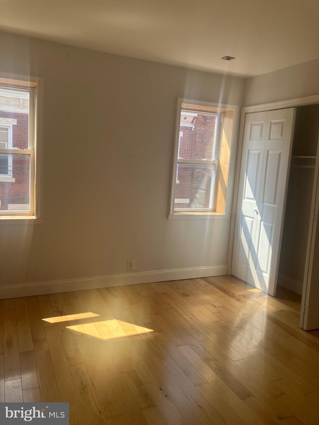 empty room with a wealth of natural light and light hardwood / wood-style floors