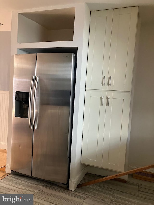 kitchen with light hardwood / wood-style flooring, white cabinets, and stainless steel refrigerator with ice dispenser