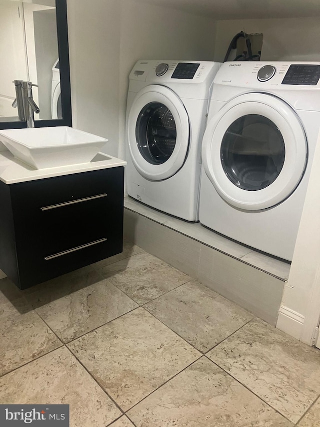 washroom with light tile patterned floors, sink, and washing machine and clothes dryer