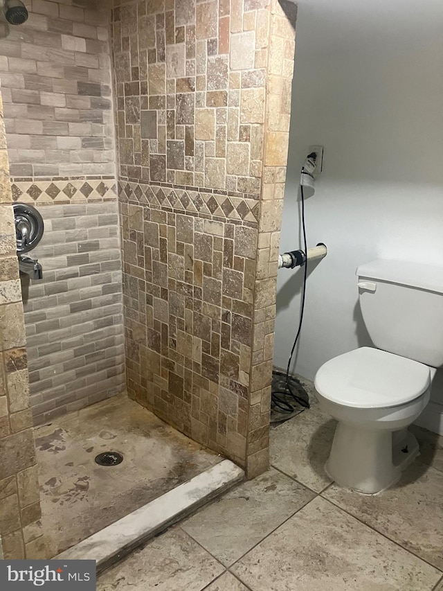 bathroom with a tile shower, tile patterned flooring, and toilet