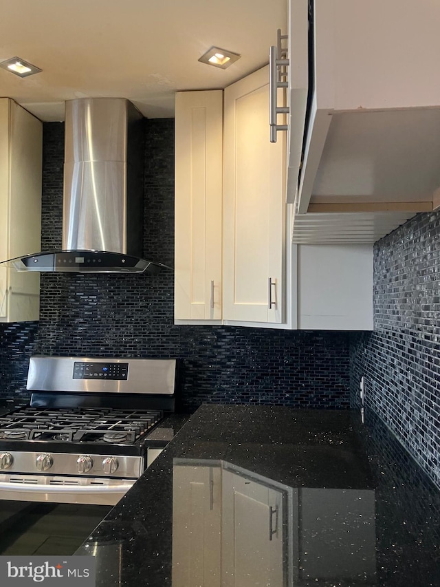 kitchen featuring tasteful backsplash, white cabinets, and wall chimney range hood