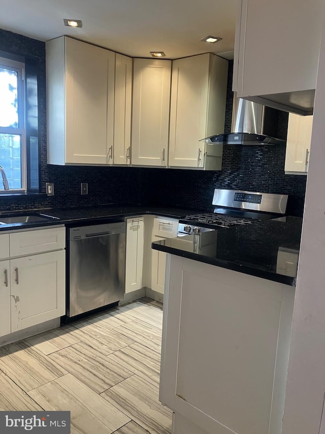 kitchen with tasteful backsplash, wall chimney exhaust hood, stainless steel appliances, sink, and white cabinetry