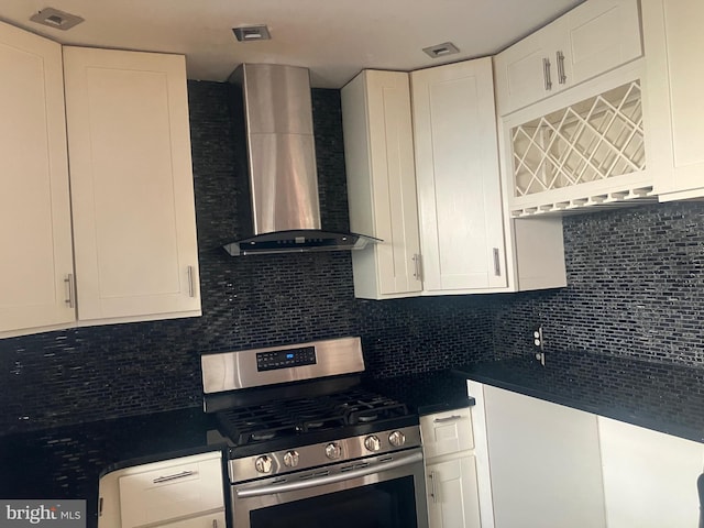 kitchen featuring backsplash, gas range, white cabinetry, and wall chimney exhaust hood