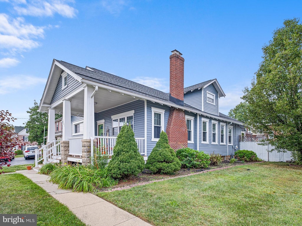 view of side of property with a porch and a yard