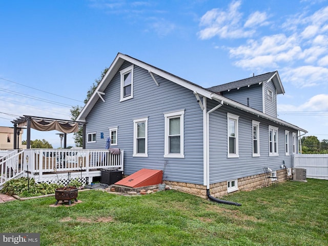 rear view of property with a lawn, a pergola, cooling unit, and a deck