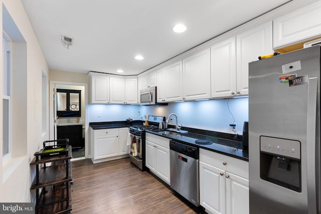 kitchen with white cabinets, appliances with stainless steel finishes, dark wood-type flooring, and sink