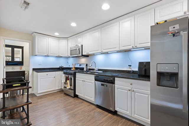 kitchen with stainless steel appliances, white cabinetry, dark hardwood / wood-style floors, and sink