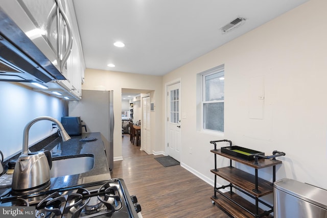 kitchen with white cabinets, stainless steel refrigerator, dark wood-type flooring, and sink